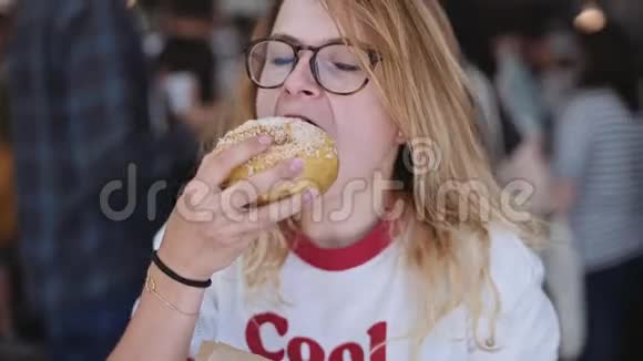 金发女孩咬一口美味的甜甜圈视频的预览图