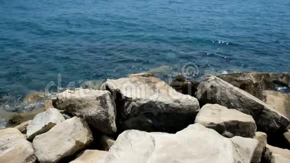 在晴朗的日子里特写一片石滩海滩上的岩石和鹅卵石淹没了浪花和海浪视频的预览图