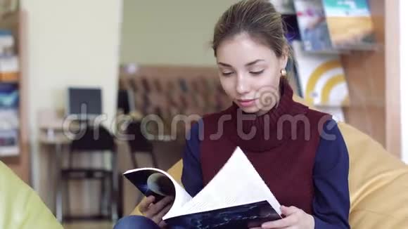 微笑浪漫女学生在阅览室翻阅一本书的画像视频的预览图