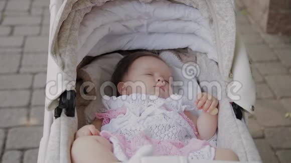 漂亮的小女孩睡在街上的婴儿马车里视频的预览图