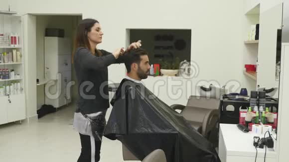 女性和男性理发师正与理发店的客户合作在理发店里剪头皮视频的预览图