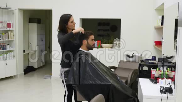 女性和男性理发师正与理发店的客户合作在理发店里剪头皮视频的预览图