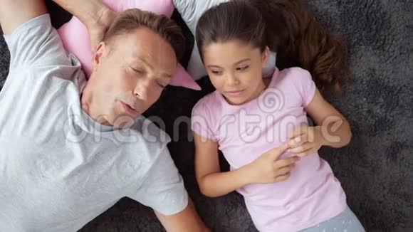 快乐的男人和他的小女儿在家里躺在地板上视频的预览图