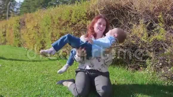 幸福的家庭在草坪上休息妈妈用温柔和爱和孩子玩儿子笑他玩得很开心快乐视频的预览图