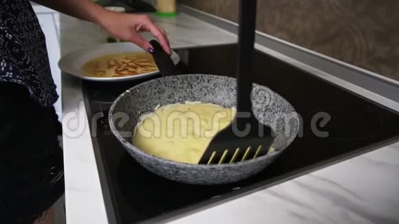 一只拿着抹刀的母手把煎饼推到锅周围然后把它转过来自制煎饼慢镜头视频的预览图