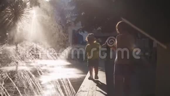 妈妈和她的孩子在喷泉附近的公园里散步视频的预览图