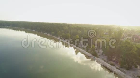4K空中录像日出时在平静的湖面上靠近森林海岸飞行视频的预览图