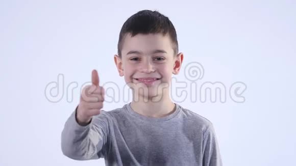 微笑的男孩把拇指举起来孤立在白色的背景上视频的预览图