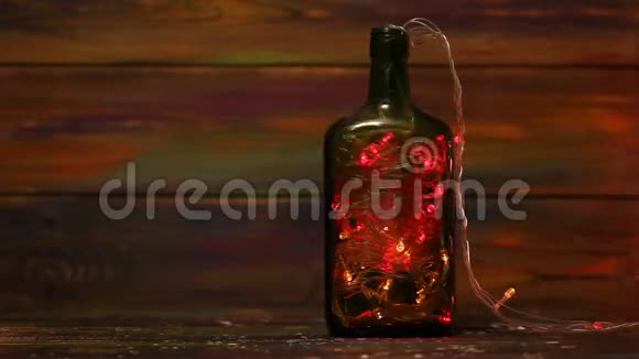 圣诞装饰品木质背景上瓶子里的发光花环视频的预览图