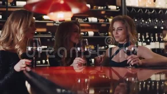 三个有魅力的女朋友举起酒杯举杯欢呼喝酒有酒的架子视频的预览图