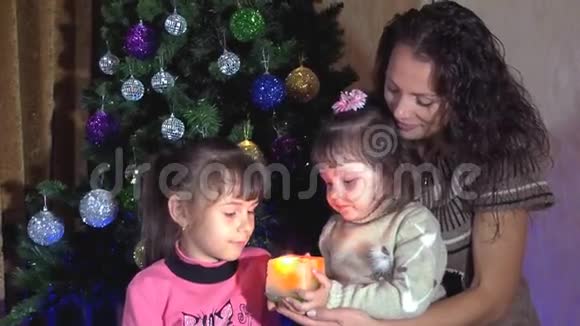 一家人在圣诞树下拿着蜡烛妈妈和女儿们拿着蜡烛在圣诞树上一个小孩带着视频的预览图