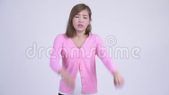 年轻迷茫的亚洲女人在竖起大拇指和大拇指之间做出选择视频的预览图