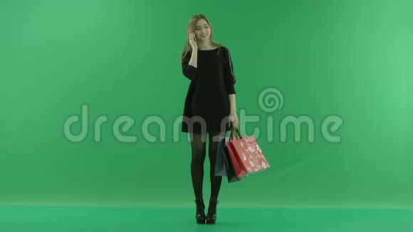 带着购物袋的年轻女性在智能手机上交谈色度键绿色背景视频的预览图