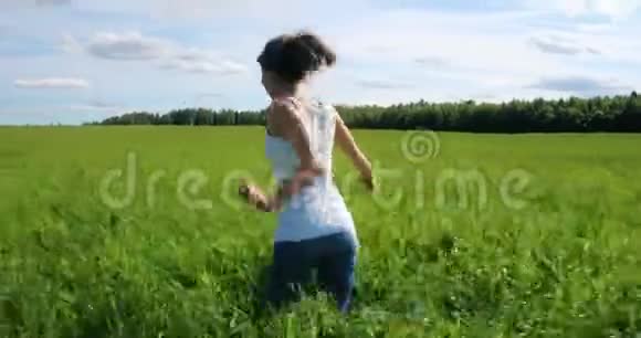 快乐美丽的女孩跑在田野的草地上视频的预览图