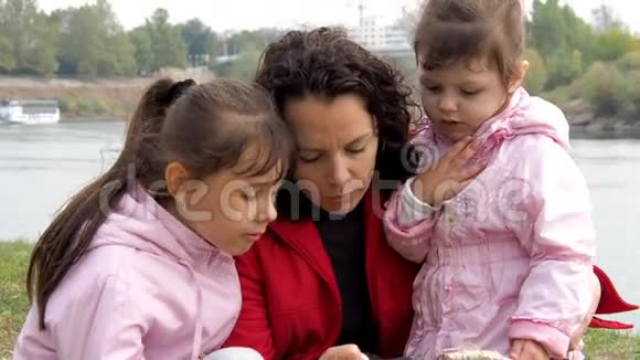家人看手机妈妈用手机给两个女儿看东西背景情况视频的预览图