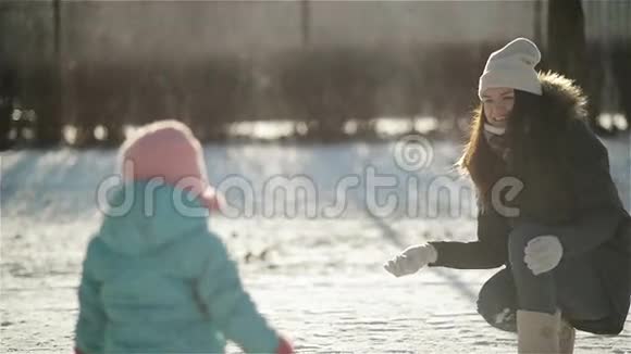 年轻的妻子在冬天给她的孩子扔雪球母亲和女儿正在享受寒冷的阳光视频的预览图