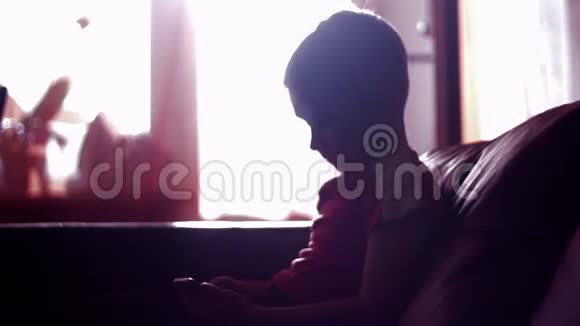 一个小男孩在家里玩智能手机游戏的剪影视频的预览图