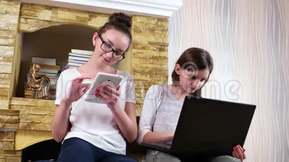 两个年轻漂亮的女孩在家里使用小工具的肖像朋友在家里用设备社交视频的预览图