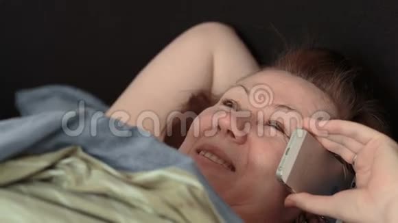 床上的女人用电话说话视频的预览图
