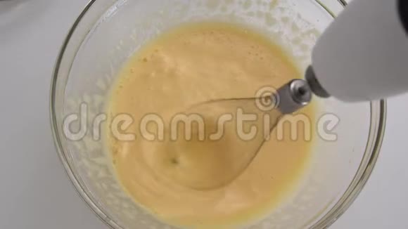 靠近玻璃碗中的搅拌鸡蛋和电动搅拌器视频的预览图