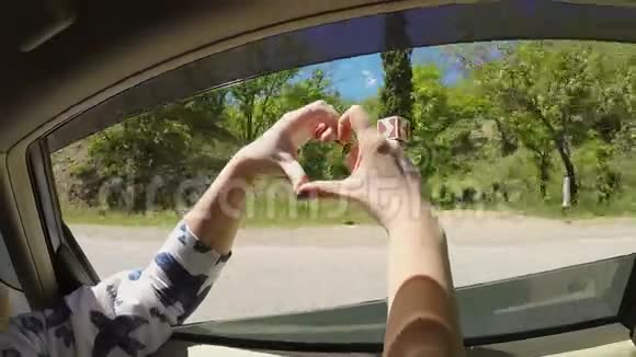 一位年轻女子从车窗里的手里掏出心脏视频的预览图