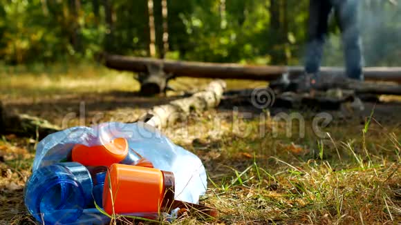 一个装有塑料垃圾的包裹躺在一片空地上燃烧着火焰人们在后台散步野营和大自然视频的预览图