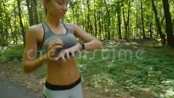 年轻的女运动员在户外练习健身并设置她的有氧运动监视器智能手表视频的预览图
