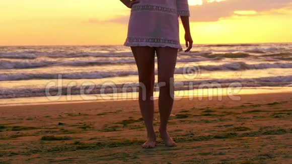 在日落时赤脚的少数民族女孩穿着白色连衣裙在海滩上视频的预览图
