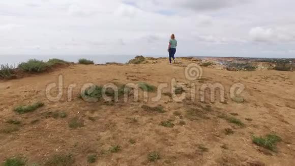 年轻女子走在海边的岩石上视频的预览图