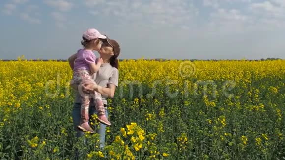 母亲在大自然中拥抱她的女儿带着小女孩在黄田的女人一个幸福的家庭视频的预览图