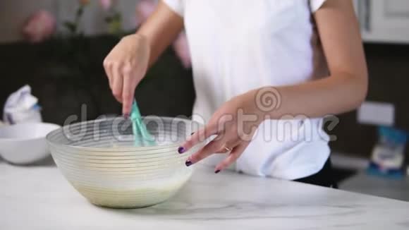 无法辨认的女人用搅拌器在碗里准备面团混合原料自制食物慢镜头视频的预览图