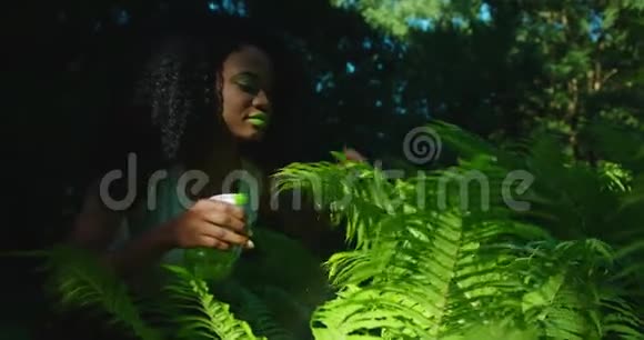 绿色构图这位美丽的美国黑人妇女涂着绿色的口红和眼影正在照顾这种蕨类植物她是视频的预览图