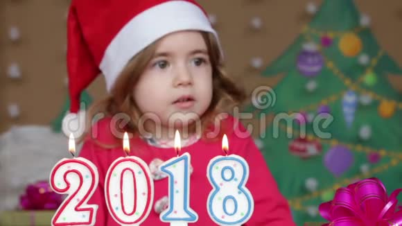 戴着圣诞老人帽子吹灭蜡烛的漂亮小女孩特写镜头视频的预览图