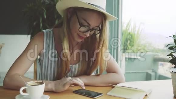 困惑的年轻女孩在手机上和朋友聊天女人在咖啡馆的智能手机上写按摩视频的预览图