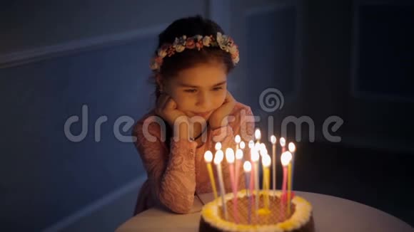 一个小女孩在一个有蜡烛的生日蛋糕附近特写视频的预览图