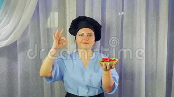 女人穿着围裙做饭微笑着手里拿着绿色沙拉举手好吗视频的预览图