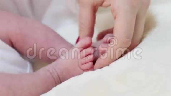 女人的手触摸房间里床上婴儿有趣的小脚视频的预览图