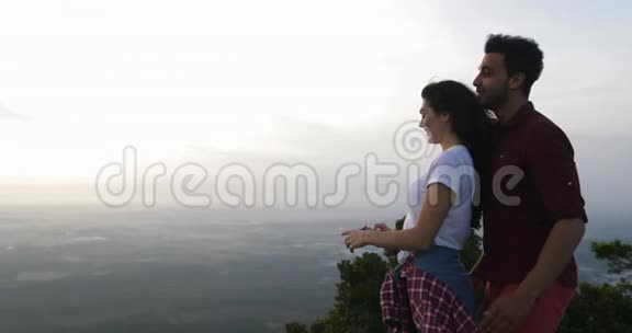 山顶上的一对情侣用手机拍照日出时男女拥抱视频的预览图