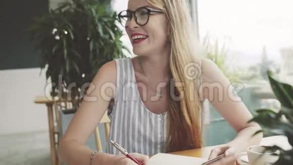 年轻的女人笑着手里拿着卡片写在笔记本上女学生开玩笑和学习视频的预览图