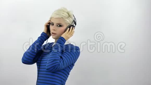 金发女人用耳机听音乐视频的预览图