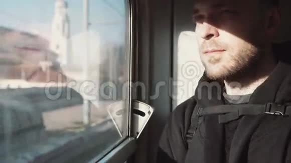 英俊的年轻人坐火车旅行有魅力的男性看着窗户思考坐在阴影中视频的预览图