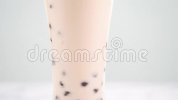 在酒杯中搅拌木薯珍珠泡奶茶在明亮的大理石桌上品尝台湾流行的美味饮料自制概念视频的预览图