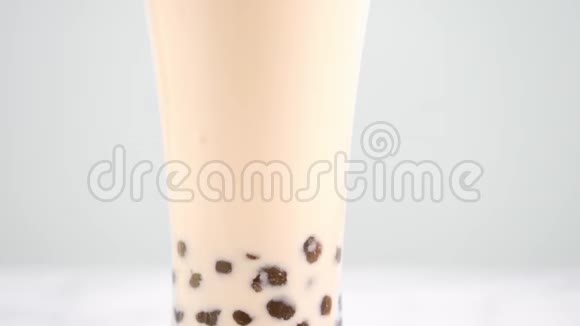 在酒杯中搅拌木薯珍珠泡奶茶在明亮的大理石桌上品尝台湾流行的美味饮料自制概念视频的预览图