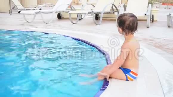 小男孩正坐在度假村的池边视频的预览图