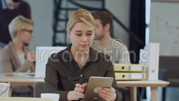工作场所漂亮的年轻女性使用数码平板电脑视频的预览图