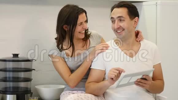 幸福夫妻在厨房餐桌前使用餐桌视频的预览图