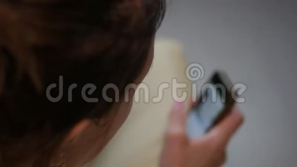 年轻女子坐在床上用手机做网上购物网上购物的概念视频的预览图