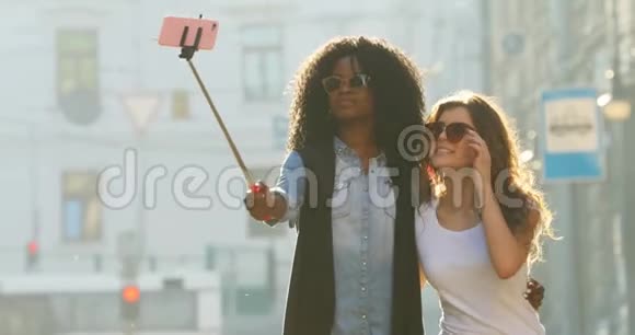 两个多民族女朋友欢乐散步的慢动作观微笑的女孩正在矫正太阳镜视频的预览图