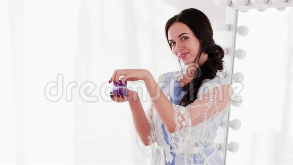 在紫罗兰色的罐子里测试每日香喷喷的面霜微笑的女孩拿着一罐护肤品视频的预览图
