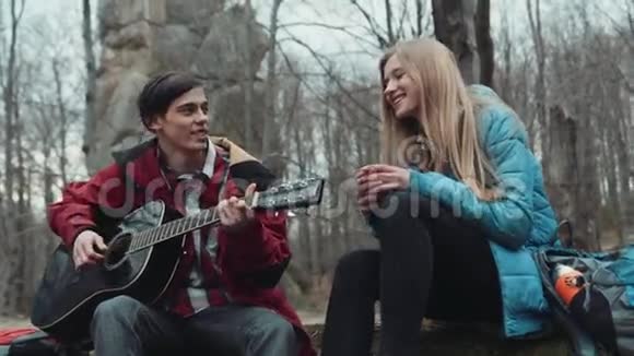 迷人的小男孩弹吉他的迷人的金发欧洲女朋友谁喝茶他们正在笑视频的预览图